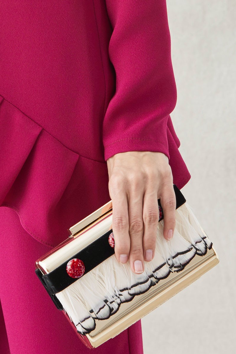 clutch de fiesta de laton dorado con plumas blancas y negras y piedras rojas para invitadas de boda apparentia