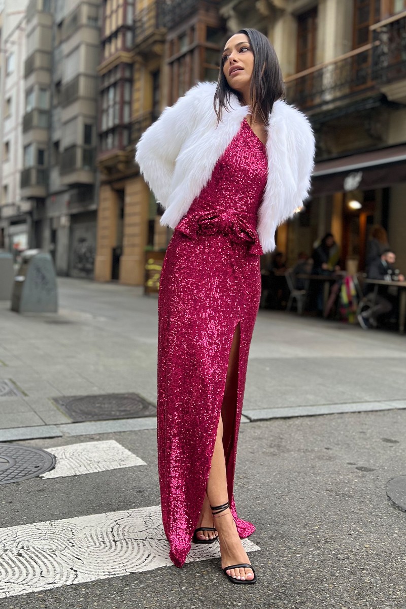 Vestido largo asimétrico de lentejuelas rosa fucsia con cinturon con lazo y abertura en la falda  para invitadas bodas compra online chaqueta pelo blanca